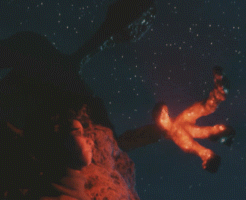 alien putting his big glowing red hand towards a boy's face